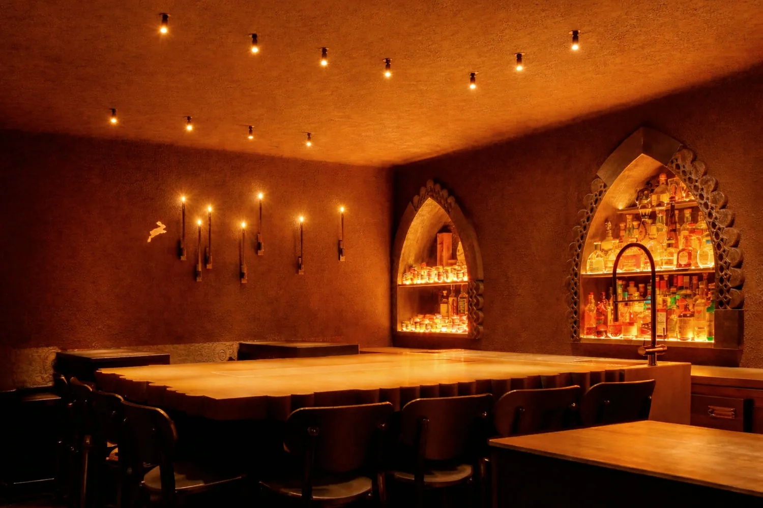 Зал El Copitas Bar в Петербурге: свечи на стенах, стол со стульями, бутылки в подсвеченных арочных нишах