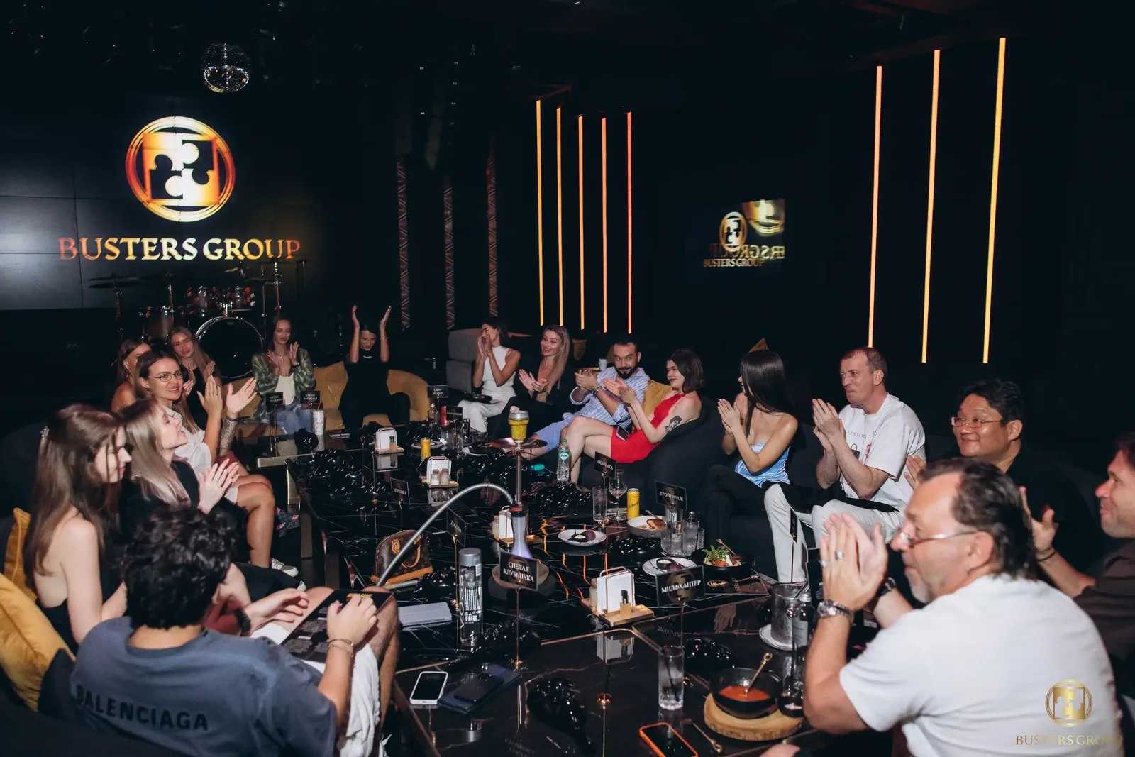 Игровой зал Busters Group — гости за столом под фирменным логотипом